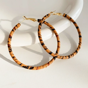 Détail de boucles d'oreilles créoles léopard en cuir sur céramique blanche élégante