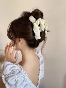 Detail of cream pleated fabric hair claw clip used for French twist hairstyle on female model