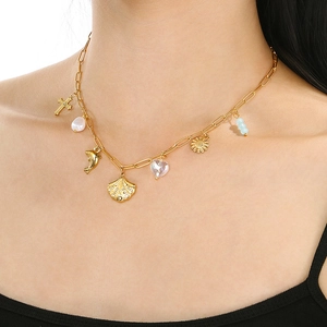 Detail of gold paperclip chain necklace with sea shells and mixed charms on a model