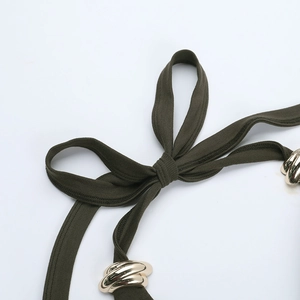 Détail de bretelles en maille vert olive avec ferrures dorées et nœud décoratif élégant
