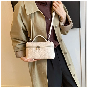Professional beige litchi grain leather box handbag shown by a model wearing a trench coat