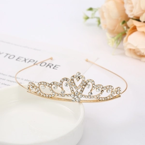 Close-up of golden bridal crown with sparkling rhinestones on an elegant ceramic tray