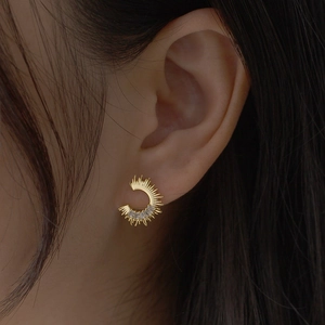 Detailed view of C-shaped gold earring with baguette cubic zirconia on model's ear
