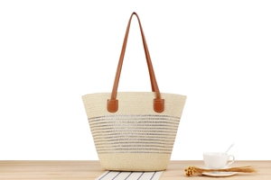 Detailed close-up of beige woven tote bag with silver stripes and brown leather straps