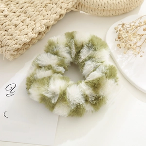 Close-up of plush velvet scrunchie with green checkered pattern on a creamy background