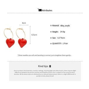 Detailed view of red acrylic heart hoop earrings with silver needle on white background