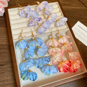 Détail de boucles d'oreilles fleurs en tissu avec perles en violet, bleu et rose