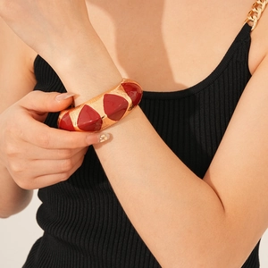 Detail of vintage gold open bangle with deep red enamel inlay worn on wrist