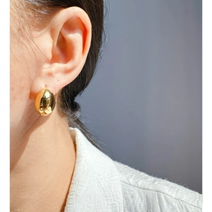 Polished gold teardrop earrings in minimalist metal style shown on a female model