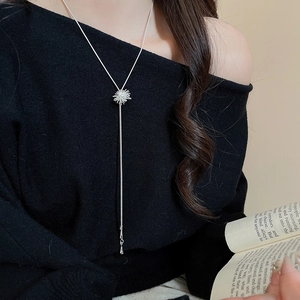 Detail of silver starburst pendant necklace with long tassels worn by a model