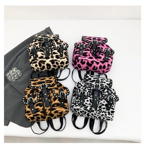 Flat lay of leopard print mini backpacks featuring metallic studs and leather buckle details