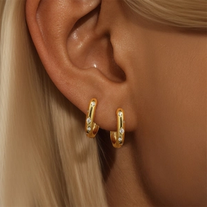 Detail of gold-plated hoop earrings with sparkling micro-pave zircons on a female ear