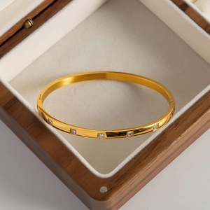 Détail d'un bracelet plaqué or 18K avec zircons blancs posé sur une boîte en bois