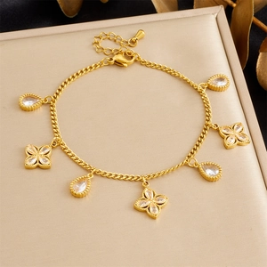 Detail van de gouden armband met druppel- en bloembedeltjes op een luxe standaard
