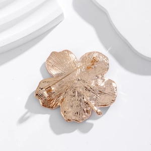 Rose gold clover metal brooch back view showing safety pin and polished texture