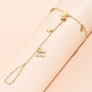 Detail view of gold chain hand bracelet with butterfly and star charms on wrist