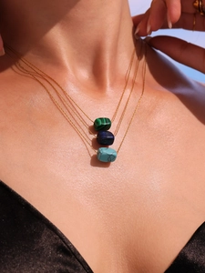 Close-up of three layered gold necklaces with rectangular malachite and lapis pendants