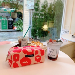 Primer plano de estuche con estampado de leopardo rosa y cremallera metálica en mesa