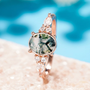 Macro shot of oval moss agate ring with zircon accents in rose gold finish
