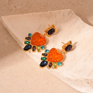 Detail of vintage heart earrings with orange resin stone and multi-colored rhinestones