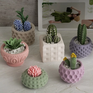 Miniature succulent arrangements in assorted geometric textured silicone pots on marble