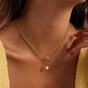 Double-layered 18K gold stainless steel necklace with bow and heart pendants on model