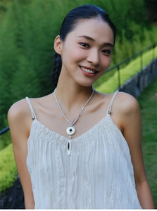 Silver-toned minimalist necklace with black enamel disc pendant worn by a female model