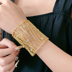 Close-up of wide gold mesh woven bracelet with sparkling crystal accents on model