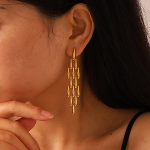 Vue détaillée de boucles d'oreilles dorées à franges étagées avec plaques en métal