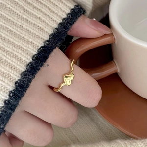 925 silver minimalist heart ring with twisted gold band shown on a hand with coffee