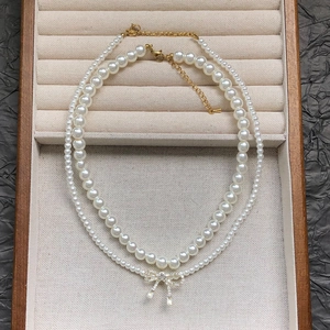 Elegant double-layer pearl necklace with a sparkling zircon bow pendant in a jewelry box