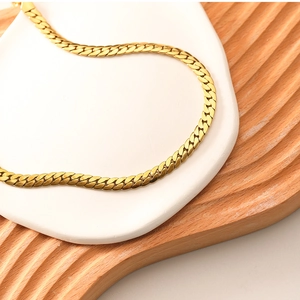 Detail shot of flat 18k gold-plated stainless steel snake chain on a white tray