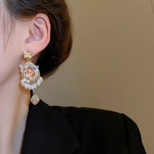 Detail of vintage gold bow earrings with crystal water drop pendants on a model
