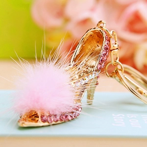 Close-up of pink crystal high heel keychain with fluffy pompom and gold lobster clasp