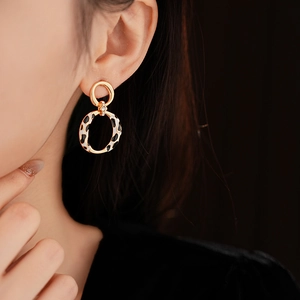 Macro detail of golden round earrings with leopard print and sparkling crystal on model