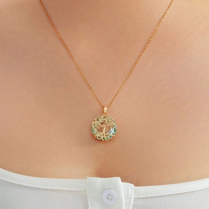 Golden Tree of Life necklace with green and blue stones worn by a model in a close-up view
