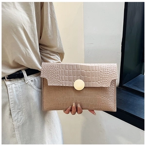 Detail of beige crocodile embossed envelope clutch bag with gold round metal buckle decoration