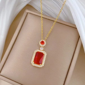 Macro shot of titanium gold necklace with red rectangular gemstone and zircon accents