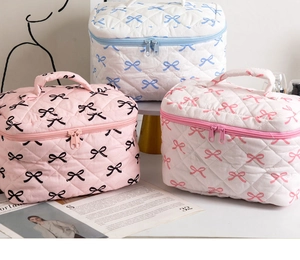 Three quilted cotton makeup bags with bow patterns, top handles and dual zippers