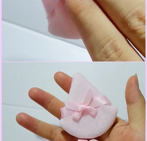 Macro detail of a soft pink teardrop velvet powder puff with a cute decorative ribbon bow