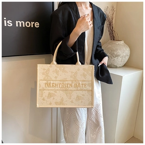 Detailed butterfly embroidery texture on the beige canvas large tote bag