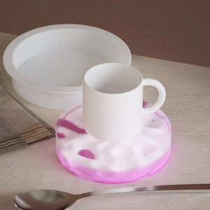 Detailansicht eines rosa Harz-Untersetzers mit einer weißen Keramik-Kaffeetasse