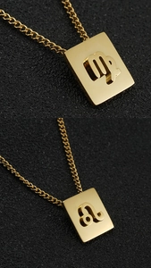Macro detail of gold-plated square zodiac pendants for Leo and Virgo on a black surface