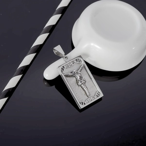 Polished silver crucifix pendant necklace in stainless steel on a dark reflective surface