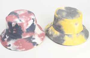 Detail of two tie-dye canvas bucket hats in pink and yellow color schemes on white back
