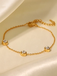 Détail du bracelet plaqué or 18K avec pierres de zircon sur tissu en soie blanche