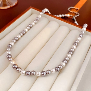 Detailed macro of white and grey pearl necklace with silver chain in jewelry box