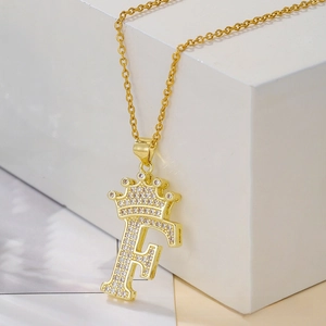 Detailed close-up of golden crown letter F pendant necklace with pavé zircon setting