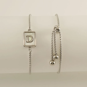 Detail of adjustable stainless steel bracelet featuring a shell letter D pendant
