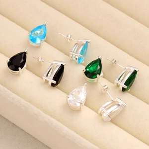 Macro shot of colorful teardrop gemstone earrings on beige velvet display tray